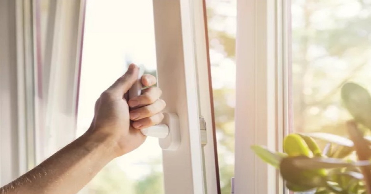 Mão a abrir a janela para permitir a entrada de ar fresco. Arejar e ventilar as divisões é a dica mais simples para evitar humidade e condensação